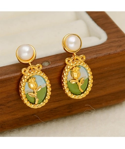 Detailed macro view of vintage pearl earrings with gold rose relief on enamel