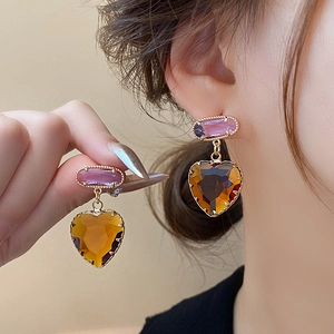 Elegante herzförmige Ohrhänger mit bernsteinfarbenen und lila Zirkonia getragen von einem Model