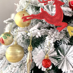 Dettaglio di renne rosse e ornamenti dorati glitterati su un albero di Natale bianco