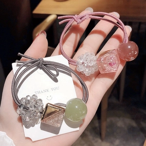 Detailed view of elastic hair bands with gray and pink crystal beads held in hand