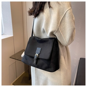 Vista laterale di borsa nera in nylon opaco con fibbia in pelle e chiusura in metallo