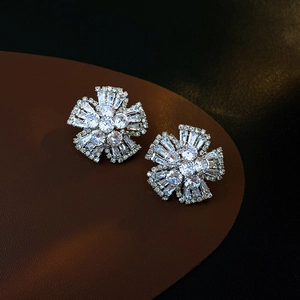 Détail de boucles d'oreilles fleur en argent et zircons sur support en cuir marron