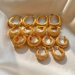 Macro view of assorted 18K gold plated hoop earrings with textured patterns on silk