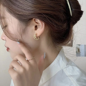 Eleganti orecchini a cerchio dorati a forma di C e anello ondulato su una modella donna