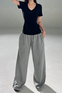 Detail of a black V-neck short sleeve T-shirt with grey wide-leg drawstring trousers