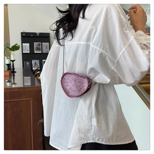 Detail of pink heart-shaped crystal mini bag with silver chain strap on model