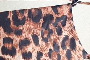 Detailed macro view of silky leopard print fabric with thin shoulder strap on dress
