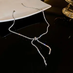 Elegant zircon bow pendant necklace with silver chain on reflective black surface