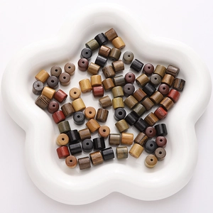 Assorted natural wooden cylindrical spacer beads in a white floral tray for DIY jewelry