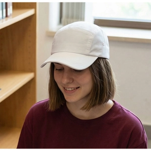 Side view of a woman wearing a minimalist white five-panel camper cap in a library