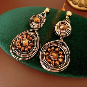 Macro shot of vintage woven round dangle earrings with copper beads on green velvet pad