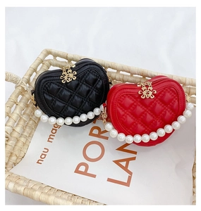 Detail of heart-shaped quilted mini bags with pearl handles in black and red colors