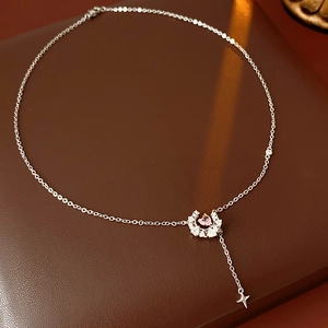 Détail d'un collier argenté avec pendentif coeur rose et breloque étoile sur cuir