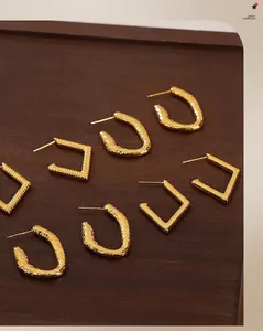 Detail of gold geometric earrings showing textured square and hammered oval designs