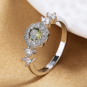 Close-up of a flower-shaped silver ring with a green gemstone and diamond accents