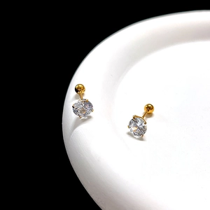 Macro detail of clear zircon stud earrings with golden screw back on white porcelain