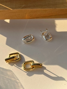 Detailed close-up of geometric U-shaped silver and gold earrings with polished mirror finish