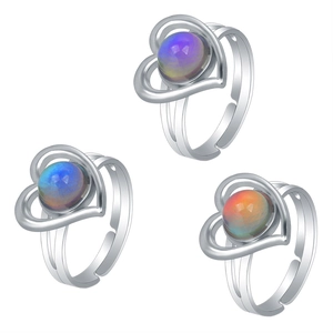 Detailed shot of three silver heart-shaped mood rings with color-changing gemstones