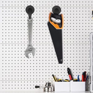 Strong black magnetic hooks on a white pegboard holding a wrench and a hand saw