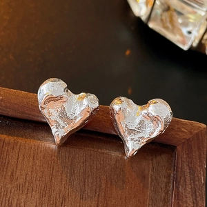 Macro de boucles d'oreilles cœur argentées avec texture lave sur support en bois