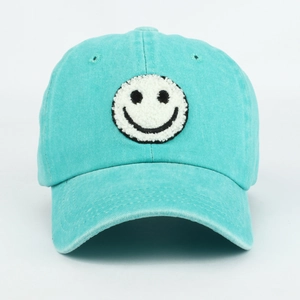 Detailed view of chenille smiley face patch on mint green washed cotton baseball cap