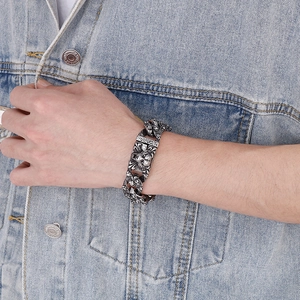 Detail of vintage silver tiger head steel chain bracelet worn over denim jacket