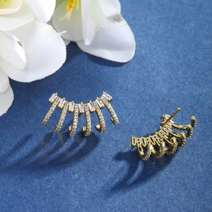 Detail view of gold geometric heart earrings with cubic zirconia on blue texture