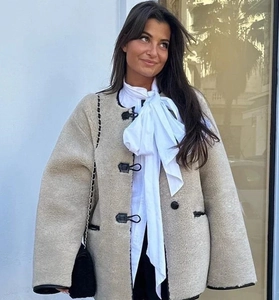 Détail d'une veste en peau lainée beige avec des fermoirs à bascule en cuir noir