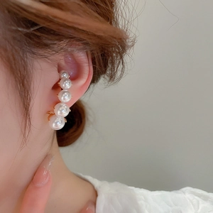 Detail view of five gradient pearls ear climber in gold finish on a woman's ear
