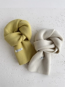 Dettaglio ravvicinato di sciarpe in maglia spessa gialla e beige con etichetta tessuta