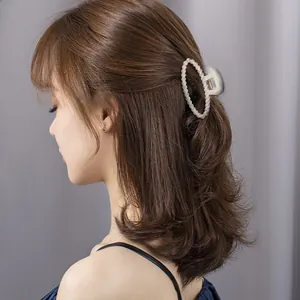 Elegant white faux pearl hair claw clip styled on a woman's brunette wavy hair
