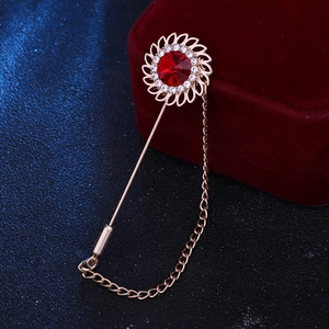 Detail of rose gold sunburst lapel pin with red crystal, rhinestones and tassel chain