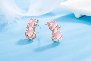 Close-up of rose gold cat stud earrings with pink crystal and sparkling clear zircon stones