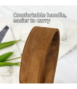 Detail of brown faux suede handle featuring reinforced stitching on a large tote bag