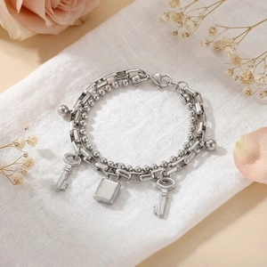Detail of double-layer stainless steel bracelet with lock and key charms on fabric