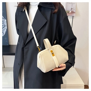 Detail of a beige vintage doctor bag with a gold metal lock worn with a black coat