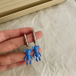 Detail of blue bear earrings with LOVE engraving and silver hoops in hand