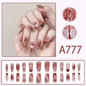 Detail view of burgundy press-on nails with butterfly, rose patterns and silver glitter