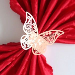 Detail of laser-cut rose gold butterfly napkin ring holding a folded red napkin