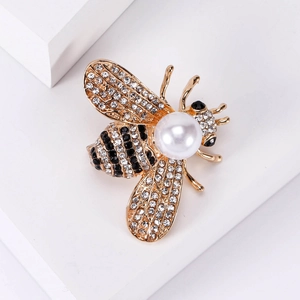 Fashion bee brooch with gold plating, sparkling rhinestones and white pearl on a white base