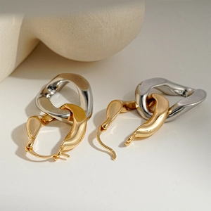 Detail of minimalist geometric gold and silver hoop earrings on a white surface