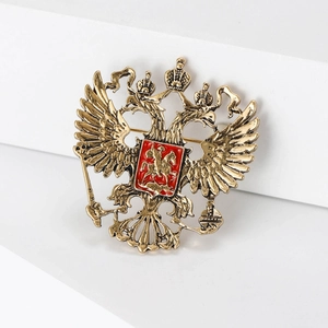 Macro detail of antique gold eagle emblem brooch with red enamel shield on white steps