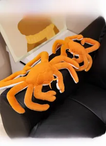 Detailed view of plush orange king crab toy with long legs on a black leather sofa