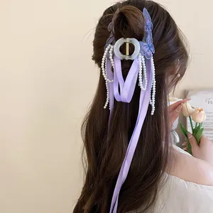Dettaglio della pinza per capelli a farfalla viola con nastro e nappe di perle