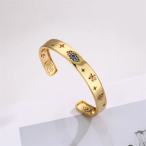 Detail of gold open bracelet featuring colorful zircon evil eye and star motifs