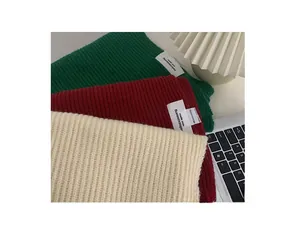 Close-up of thick knitted scarfs showing ribbed texture and minimalist woven labels