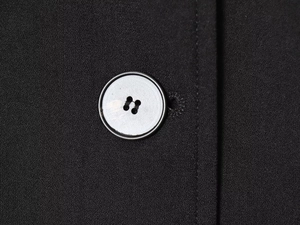 Macro view of a silver metallic button on premium black knitted fabric detail