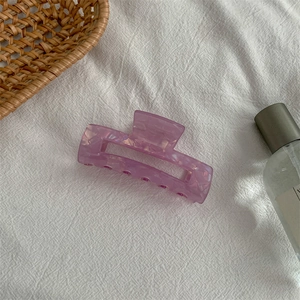 Detail view of purple marble acetate rectangle hair claw clip on white linen fabric