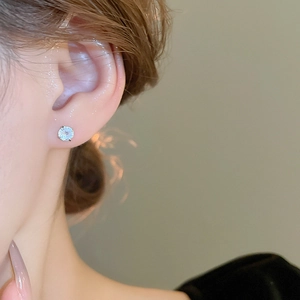 Close-up of classic silver earring with sparkling cubic zirconia on female earlobe