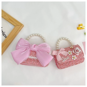 Detailed view of pink tweed kids handbags with ribbon bows and pearl handles in chic style
